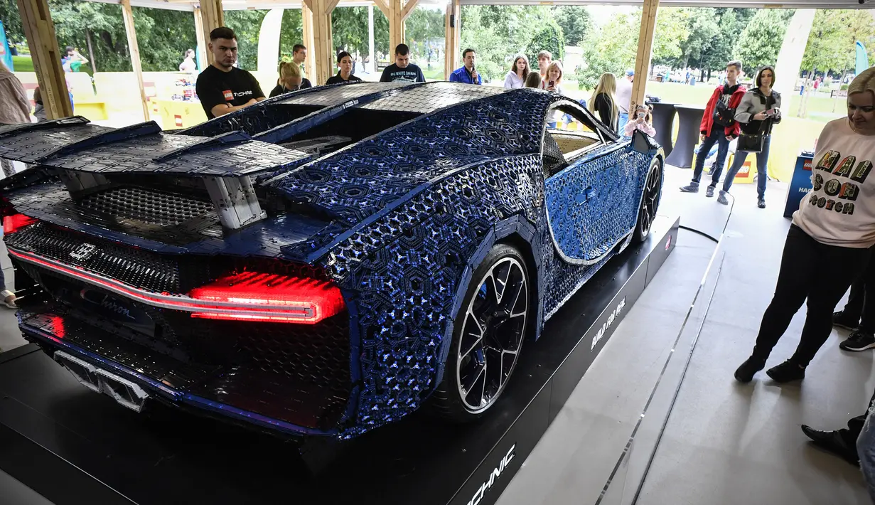 Pengunjung mengamati replika mobil Bugatti Chiron dari jutaan balok Lego Technic pada sebuah pameran di Taman Gorky Moskow, Selasa (23/7/2019). Mobil replika ini bisa dikendarai oleh dua orang dan mampu berakselerasi hingga kecepatan 20 km/jam. (Alexander NEMENOV/AFP)