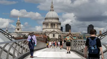 Orang-orang berjalan di Jembatan Milenium dengan latar pemandangan Katedral St. Paul di London, Inggris, 1 Agustus 2020. Pemerintah Inggris pada Jumat (31/7) mengumumkan penundaan pelonggaran beberapa langkah pembatasan menyusul jumlah infeksi virus corona yang meningkat. (Xinhua/Han Yan)