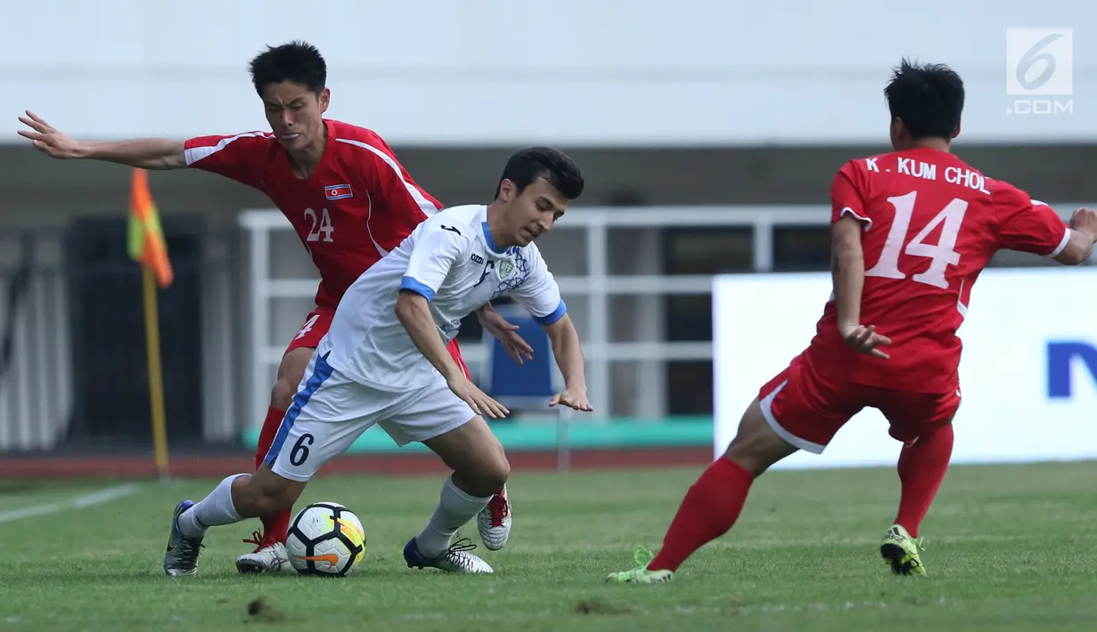 Bek Korea Utara, An Song II (kiri) berebut bola dengan pemain Uzbekistan, Nurulioev Sukhrob pada laga perdana PSSI Anniversary 2018 di Stadion Pakansari, Kab Bogor, Jumat (27/4). Laga berakhir imbang 2-2. (Liputan6.com/Helmi Fithriansyah)