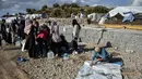 Para migran mengumpulkan air sementara yang lain membersihkan barang-barang mereka setelah hujan badai di kamp pengungsi Kara Tepe, di pulau Lesbos di timur laut Aegean, Yunani (14/10/2020).  (AP Photo/Panagiotis Balaskas)