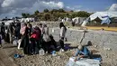 Para migran mengumpulkan air sementara yang lain membersihkan barang-barang mereka setelah hujan badai di kamp pengungsi Kara Tepe, di pulau Lesbos di timur laut Aegean, Yunani (14/10/2020).  (AP Photo/Panagiotis Balaskas)