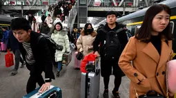 Calon penumpang membawa barang bawaan saat akan naik kereta di sebuah stasiun di Fuyang, Provinsi Anhui, China, Minggu (10/2). Pulang ke kampung halaman menjadi tradisi warga China saat Tahun Baru Imlek. (Chinatopix via AP)
