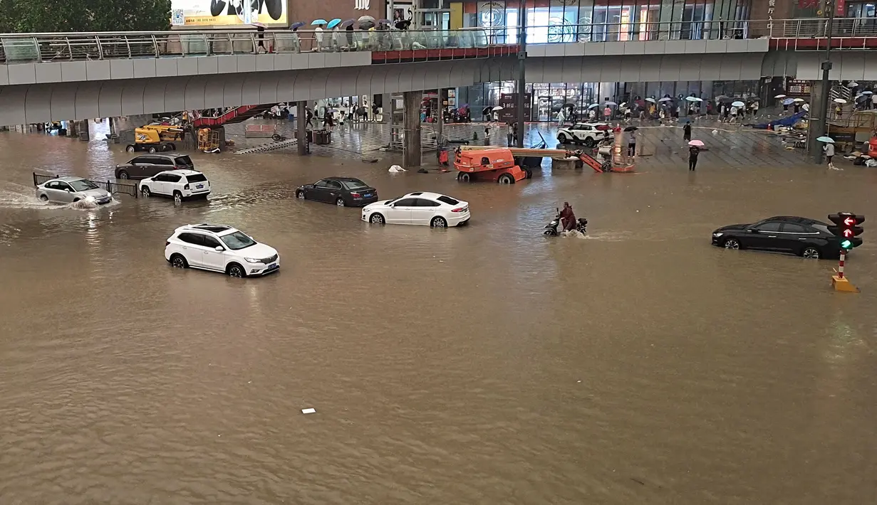Sejumlah kendaraan melintasi banjir di sepanjang jalan setelah hujan lebat di Zhengzhou di provinsi Henan, China tengah (20/7/2021). Luapan sungai menggenangi jalan-jalan dan membuat kendaraan terbawa arus setelah curah hujan 200 mm turun dalam satu jam. (AFP/STR)