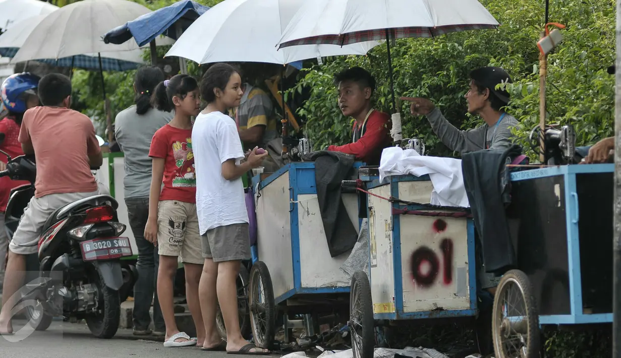Sejumlah warga menunggu pakaiannya yang sedang dikecilkan oleh penjahit keliling di kawasan Lenteng Agung, Jakarta, Senin (4/7). Menjelang hari raya Idul Fitri, penjahit 'vermak levis' keliling mulai kebanjiran rezeki. (Liputan6.com/Yoppy Renato)