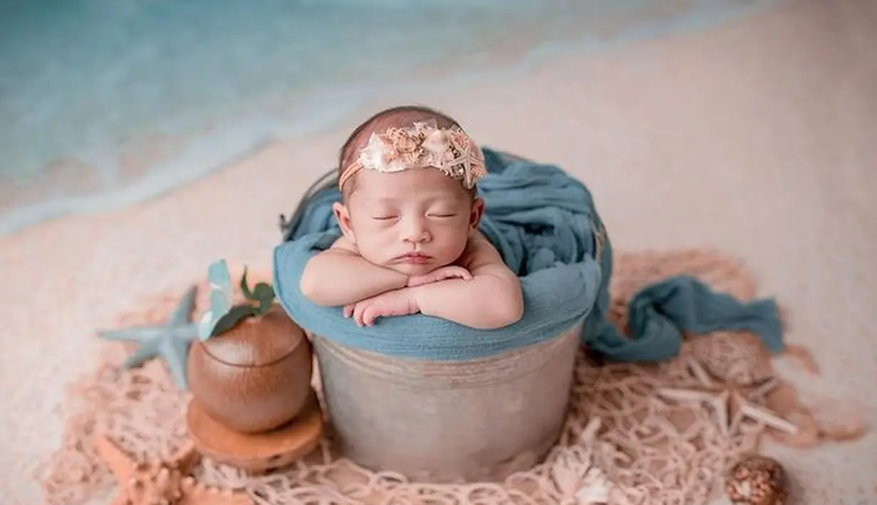 Mengambil tema pantai Baby Moana tertidur dengan pose menggemaskan di dalam sebuah ember. Heapiece dari manik-manik di atas kepalanya membuat Baby Moana terlihat cantik. (instagram/rittarrajagukguk)