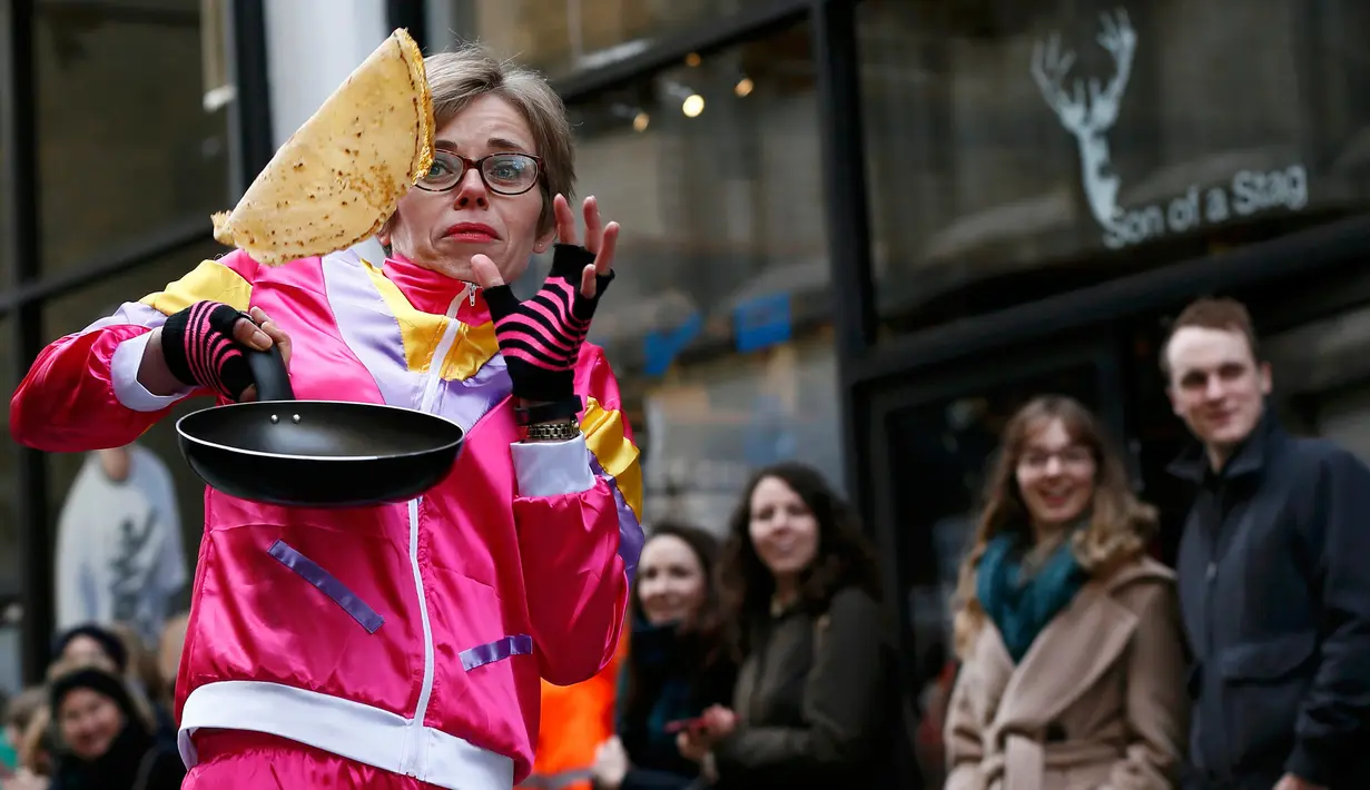 Ekpresi peserta saat membalik pancake dalam wajan ketika mengikuti acara tahunan Great Spitalfields Pancake Race untuk mengumpulkan uang bagi Ambulan Udara London di Inggris, Selasa (9/2). (REUTERS/Stefan Wermuth)