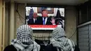 Dua pria Palestina menonton pidato Presiden AS, Donald Trump di sebuah kafe di Yerusalem (6/12). Donald Trump secara resmi mengumumkan bahwa AS mengakui Yerusalem sebagai ibu kota Israel. (AFP Photo/Ahmad Gharabli)