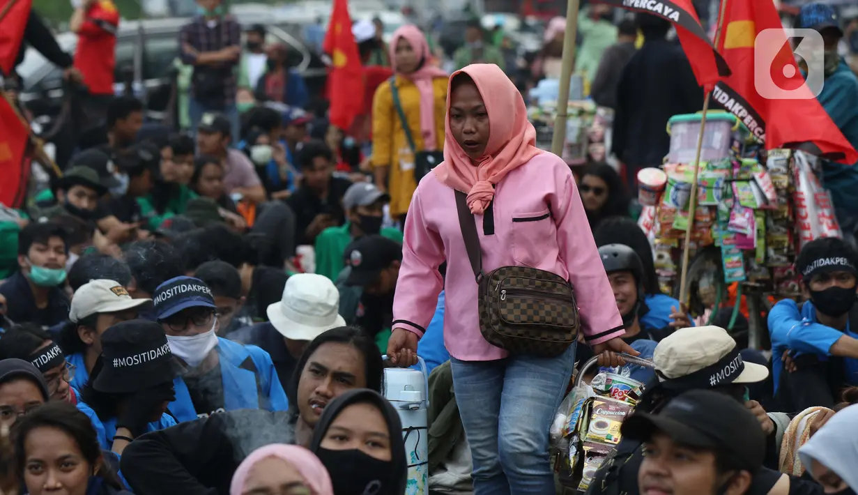 Pedagang asongan berjualan di tengah-tengah aksi unjuk rasa di kawasan Patung Kuda, Jakarta, Selasa (10/11/2020). Sejumlah pedagang mencoba peruntungan saat massa gabungan dari berbagai organisasi buruh dan mahasiswa berunjuk rasa menolak Omnibus Law UU Cipta Kerja. (Liputan6.com/Helmi Fithriansyah)