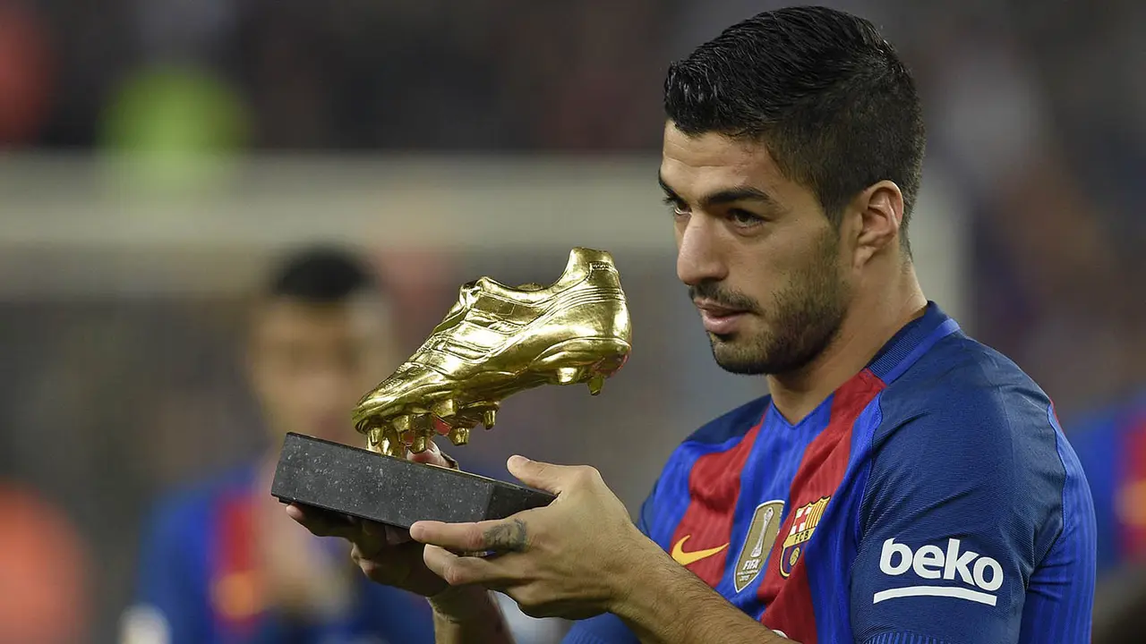 Striker Barcelona, Luis Suarez, menunjukkan Sepatu Emas musim lalu. 