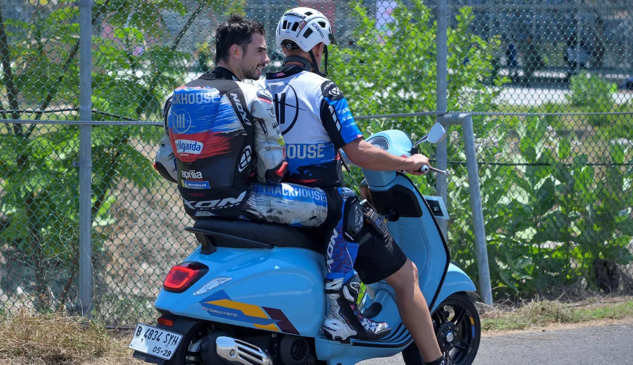 Pembalap CryptoDATA RNF MotoGP Team, Miguel Oliveira (kiri/belakang) membonceng skuter untuk kembali ke pit dalam sesi latihan bebas untuk balapan MotoGP 2024 di Sirkuit Internasional Pertamina Mandalika, Lombok, Nusa Tenggara Barat, Jumat 27 September 2024. (BAY ISMOYO/AFP)
