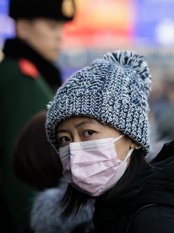 Seorang perempuan mengenakan masker penutup mulut setibanya di stasiun kereta api Beijing untuk mudik Tahun Baru Imlek pada Selasa (21/1/2020). Wabah virus korona seperti SARS yang menyebar di China dan mencapai tiga negara Asia lainnya bisa menular dari manusia ke manusia. (NICOLAS ASFOURI/AFP)