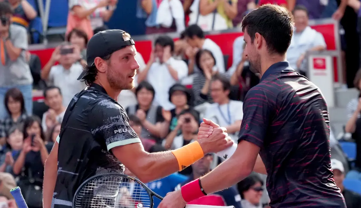 Petenis Serbia, Novak Djokovic bersalaman dengan Lucas Pouille dari Prancis usai pertandingan Tenis Jepang Terbuka 2019 di Ariake Coliseum, Tokyo, Jumat (4/10/2019). Djokovic menang dengan skor 6-1, 6-2 atas Pouille dalam durasi waktu 50 menit. (AFP Photo/Toshifumi Kitamura)