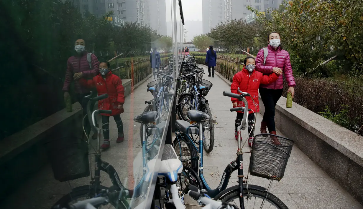 Seorang wanita membawa anak berjalan memakai masker menuju sekolah pada pagi hari di Yanjiao, provinsi Hebei, Cina (13/11). Selama lima hari ini Cina mengalami kualitas udara yang menurun karena tercemar polusi. (REUTERS/Damir Sagolj)