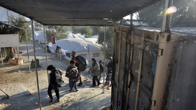 Migran berjalan di kamp pengungsi Moria saat terjadi kebakaran di pulau Lesbos di timur laut Aegean, Yunani, Rabu (9/9/2020). Otoritas kesehatan sebelumnya mengonfirmasi terdapat 35 kasus positif Covid-19 di kamp tersebut setelah melakukan pengujian sampel Covid-19 . (AP Photo/Panagiotis Balaskas)
