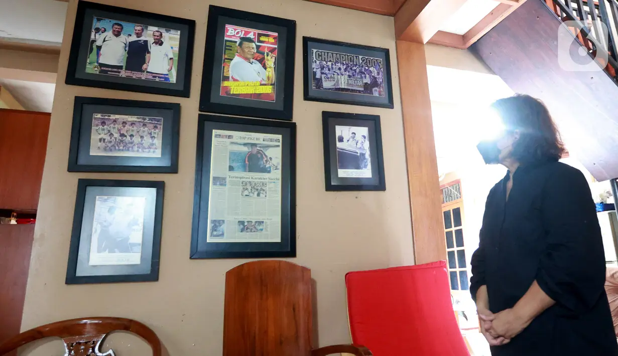 Seorang perempuan melihat foto-foto mantan pelatih Tim Nasional Indonesia, Benny Dollo saat disemayamkan di rumah duka kawasan Pamulang, Tangerang Selatan, Kamis (2/2/2023). Terlihat di samping peti jenazah terdapat beberapa medali dan piala. Salah satunya yaitu, nominasi pelatih terbaik sepak bola 2002 versi salah satu majalah di Indonesia. (Bola.com/Muhammad Iqbal Ichsan)