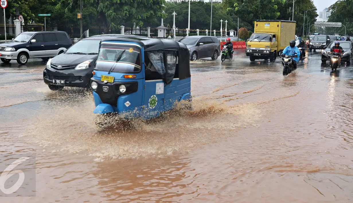Sejumlah pengendara menembus genangan air yang merendam jalan di depan Istana Merdeka, Jakarta, Selasa (9/2). Hujan deras yang mengguyur kota Jakarta membuat sejumlah jalan protokol tergenang air. (Liputan6.com/Immanuel Antonius)