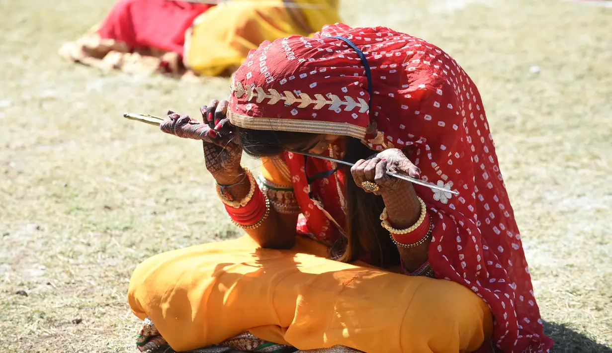 Wanita dari komunitas Shatriya menari dengan pedang dalam upaya untuk menetapkan rekor dunia dalam tarian pedang  di Rajkot,  Ahmedabad, India (28/1/2020). Acara ini bagian dari upacara penobatan tiga hari raja Rajkot ke-17, Thakorsaheb Mandhatasinh Jadeja. (AFP/Sam Panthaky)