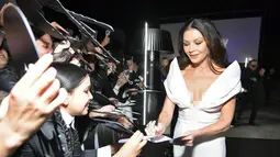 Catherine Zeta-Jones memberikan tanda tangan kepada pengemar saat menghadiri pemutaran perdana film Netfilx "Wednesday" di Los Angeles, California pada 16 November 2022. Aktris berusia 53 tahun itu memamerkan tubuhnya yang ramping dalam balutan gaun ivory yang pas dengan keliman fishtail. (Charley Gallay/Getty Images for Netflix/AFP)