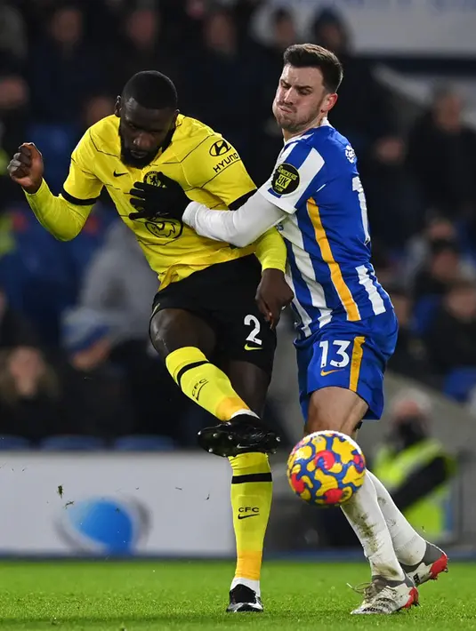 Pemain Chelsea Jerman Antonio Rudiger (kiri) berebut bola dengan pemain Brighton and Hove Albion Pascal Gross pada pertandingan sepak bola Liga Inggris di American Express Community Stadium, Brighton, Inggris, 18 Januari 2022. Pertandingan berakhir 1-1. (Glyn KIRK/AFP)
