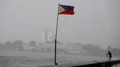 Bendera Filipina berkibar di dekat seorang warga yang memancing ditengah cuaca buruk akibat Topan Nepartak yang menerpa di Manila Bay, Filipina, Jumat (8/7). (REUTERS/Erik De Castro)