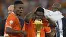 Ekspresi bahagia pemain Pantai Gading, Karim Konate (kanan) saat berdiri di samping trofi setelah laga final Piala Afrika 2023 melawan Nigeria di Alassane Ouattara Olympic Stadium, Ebimpe, Abidjan, Pantai Gading, Minggu (11/02/2024) waktu setempat. (AP Photo/Themba Hadebe)