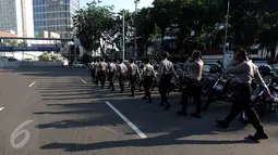 Sejumlah petugas kepolisian bersiap melakukan penjagaan di kawasan Bundaran HI, Jakarta, Senin (1/5). Seperti diketahui, puluhan ribu buruh akan berkumpul ke Ibu Kota untuk mengelar unjuk rasa peringatan Hari Buruh Internasional (Liputan6.com/Johan Tallo)