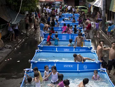 Anak-anak bermain di kolam portabel yang diberikan oleh pemerintah setempat untuk mendinginkan tubuh pada saat musim panas di Manila, Filipina (12/4). (AFP Photo/Noel Celis)
