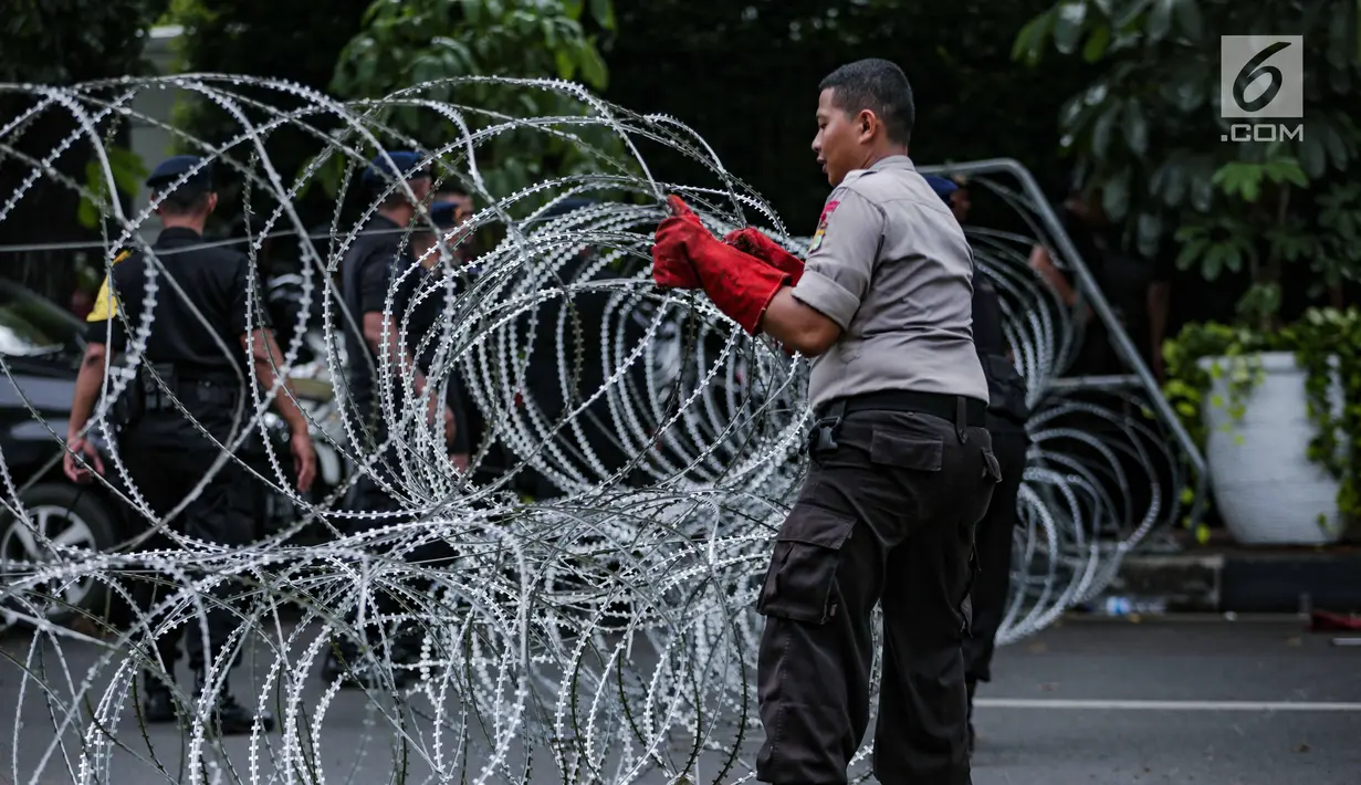 Personel kepolisian memasang kawat berduri di area gedung KPU, Jakarta, Jumat (1/3). Kawat berduri itu untuk mengantisipasi massa Forum Umat Islam (FUI) dan Gerakan Jaga Indonesia yang akan menggelar aksi di depan KPU. (Liputan6.com/Faizal Fanani)