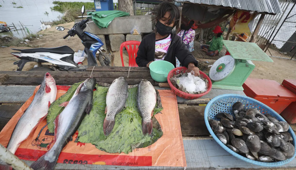 Seorang gadis Kamboja membantu keluarganya menjual ikan di sepanjang trotoar dekat desa Prek Pnov di Phnom Penh, Kamis (5/8/2021). Prek Pnov terkenal dengan peternakan ikannya dan memasok banyak pasar di Phnom Penh. (AP Photo/Heng Sinith)