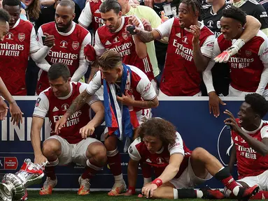Pierre-Emerick Aubameyang dari Arsenal bereaksi saat menjatuhkan trofi pada perayaan gelar juara Piala FA usai mengalahkan Chelsea pada laga final Piala FA di stadion Wembley, Minggu (2/8/2020).  Aubameyang terlihat kaget sambil memegang kepalanya saat trofi terjatuh. (Catherine Ivill/POOL/AFP)