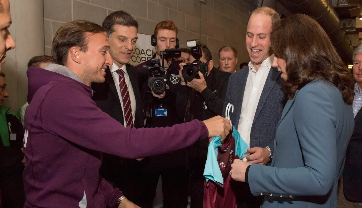 Kapten West Ham United, Mark Noble memberikan jersey kepada Pangeran William dan Kate Middleton saat mengunjungi London Stadium, Rabu (18/10). Jersey West Ham United itu diberikan untuk anak pasangan kerajaan Inggris ini, George dan Charlotte. (AP Photo)