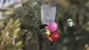 Sejumlah pria Palestina menyiapkan balon dengan alat peledak yang akan diterbangkan ke arah Israel di dekat kamp pengungsi al-Bureij, sepanjang perbatasan Israel- Jalur Gaza (12/8/2020). (AFP Photo/Mohammed Abed)