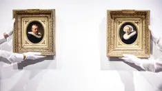 Asisten galeri memegang dua lukisan yang dikaitkan dengan seniman Belanda Rembrandt menjelang presentasi mereka di rumah lelang Christie di Amsterdam pada 21 Juni 2023. Kedua potret itu akan dilelang pada 6 Juli 2023 mendatang, di London. (Kenzo TRIBOUILLARD / AFP)