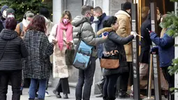 Orang-orang menunjukkan status vaksinasi mereka saat antre di depan department store terkenal 'KaDeWe' (Department Store Of The West) di Berlin, Selasa (21/12/2021). Jerman akan memperkenalkan langkah-langkah baru untuk mengekang penyebaran COVID-19 sebelum Malam Tahun Baru. (AP Photo/Michael Sohn)