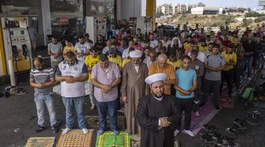 Umat Muslim melaksanakan salat Jumat di sebuah pompa bensin di kota pesisir Jiyeh, selatan Beirut, Lebanon, Jumat (3/9/2021). Sholat Jumat digelar di Pom Bensin ketika Lebanon terus bergulat dengan kekurangan bahan bakar yang menyesakkan. (AP Photo/ Hassan Ammar)