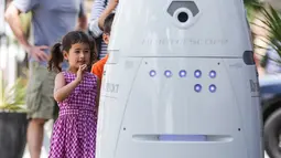 Dua orang anak berinteraksi dengan robot ROD2 di River Oaks District, Houston (18/8). Robot kemananan ini dirancang oleh Knightscope yang berbasis Silicon Valley. (Michael Ciaglo / Houston Chronicle via AP)