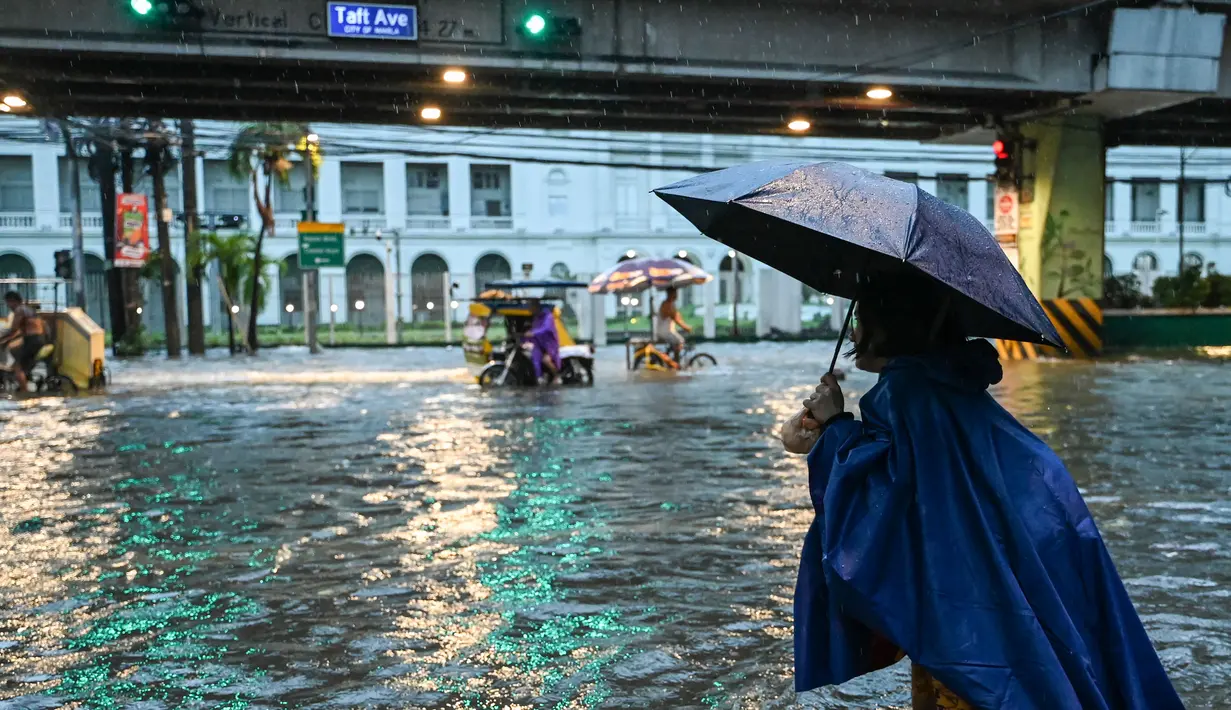 Orang-orang berjalan di sepanjang jalan yang tergenang banjir di Manila, Filipina pada 24 Juli 2024 di tengah hujan deras yang dibawa oleh Topan Gaemi. (Jam Sta Rosa/AFP)