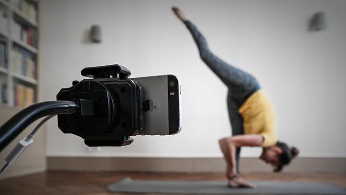 Seorang guru yoga berlatih sebelum mengajar kelas live di akun Instagram-nya pada hari kesembilan belas selama lockdown yang bertujuan untuk membatasi penyebaran infeksi COVID-19 yang disebabkan oleh coronavirus novel di Paris, Prancis (4/4/2020). (AFP/Philippe Lopez)