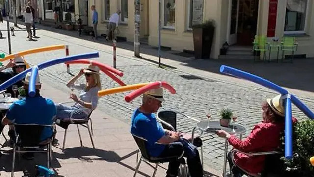 Penggunaan topi balon untuk menjaga jarak antar pengunjung di salah satu restoran di Berlin, Jerman.