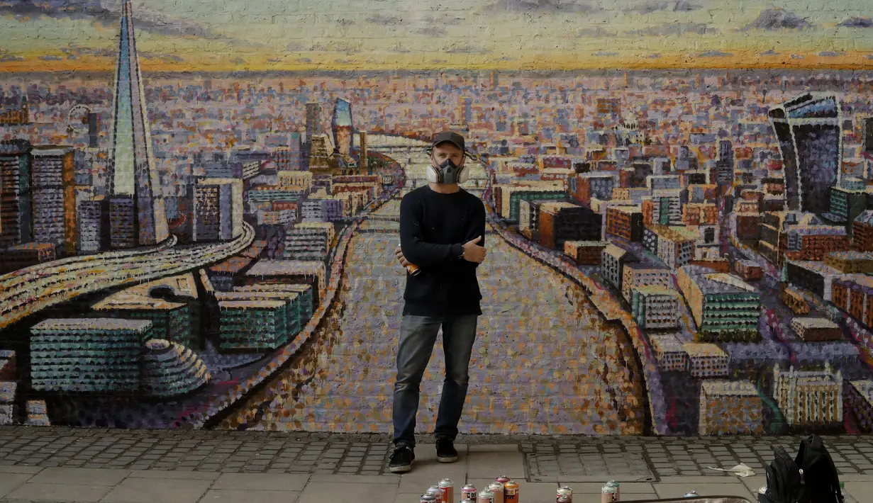 Seniman jalanan Australia James Cochran berpose di depan mural lanskap kota London buatannya di dinding Network Rail oleh Blackfriars Station, di London (5/10/2020). Ini adalah pertama kalinya Cochran melukis pemandangan kota sebagai karya seni jalanan di luar studionya. (AP Photo/Matt Dunham)