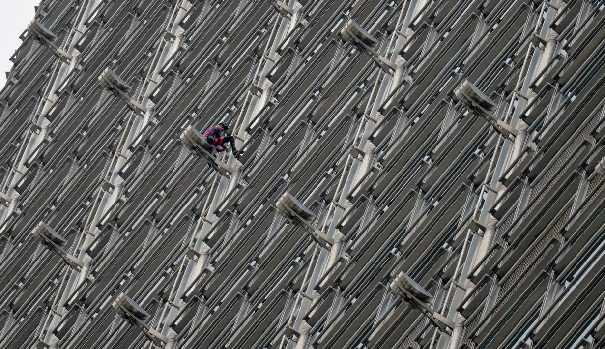 Alain Robert yang dijuluki 'French Spiderman' memanjat gedung pencakar langit Cheung Kong Center di Hong Kong, Jumat (16/8/2019). Alain Robert membentangkan spanduk perdamaian ketika pusat bisnis tersebut mengalami masalah internal dan maraknya demonstrasi. (AP Photo/Vincent Thian)