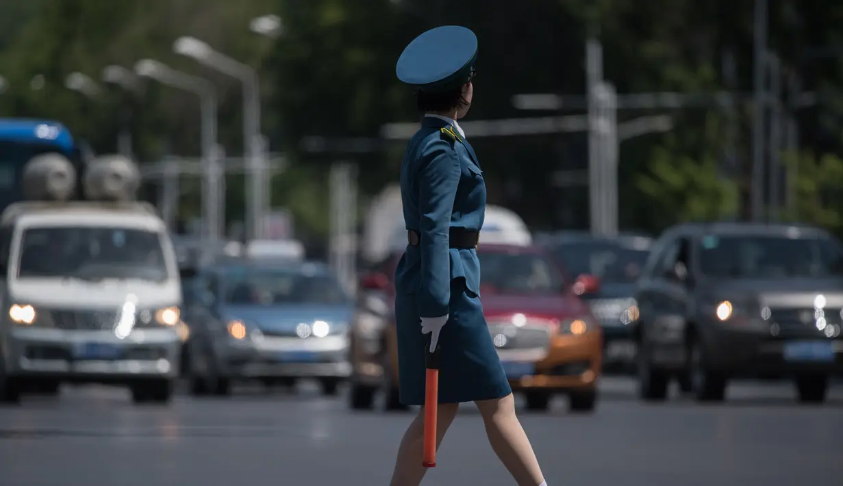 Seorang polisi wanita berada ditengah jalan untuk mengatur lalu lintas di Pyongyang, Korea Utara (5/6). Di Korea Utara menjadi polisi lalu lintas dipandang sebagai pekerjaan yang bergengsi. (AFP Photo/Ed Jones)