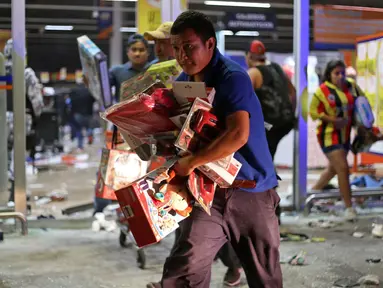 Seorang warga Meksiko membawa mainan saat menjarah toko di pelabuhan Veracruz, Meksiko, (4/1). Keputusan pemerintah Meksiko menaikkan harga Bahan Bakar Minyak hingga 20 persen per tanggal 1 Januari 2017 memicu amarah warganya. (AP Photo/Ilse Huesca)