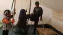 Jasim Abudllah dibantu ibunya mengenakan celana di kamp Debaga, di pinggiran Erbil, Irak (24/11). Bocah berumur 13 tahun tersebut, terpaksa harus kehilangan kaki kanannya akibat terkena serangan udara di Baiji. (Reuters/Mohammed Salem)