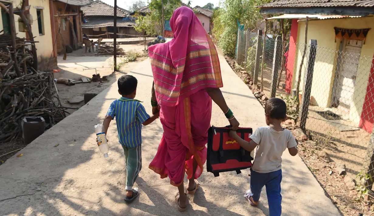 Savita Kedar ditemani oleh cucunya usai menimba ilmu di Sekolah Aajibaichi Shaala, Desa Fangane, India, pada 1 Maret 2017. Sekolah ini memulai kegiatan belajar sekitar pukul dua siang waktu setempat. (AFP Photo / Indranil Mukherjee)
