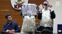 Wakil Ketua KPK, La Ode Muhammad Syarif (kiri) melihat barang bukti uang hasil OTT di Gedung KPK, Jakarta, Sabtu (26/6/2019). Dalam OTT tersebut, KPK menyita uang 20.874 dolar Singapura, 700 USD dan Rp 200 juta dari lima tersangka. (Liputan6.com/Helmi Fithriansyah)