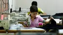 Bocah pengungsi Suriah bernama Muhamed saat menjahit kain di sebuah pabrik tekstil, Istanbul, Turki, (24/6). Meski seumurannya masih menikmati bangku sekolah, mereka menikmati pekerjaan mereka. (REUTERS/Murad Sezer)