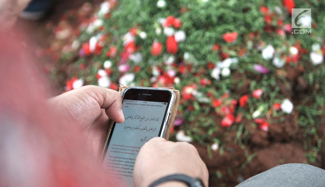 Putra pertama Presiden ke-3 RI BJ Habibie, Ilham Akbar Habibie membaca Alquran dari handphone saat berziarah ke makam kedua orangtuanya di TMP Kalibata, Jakarta, Minggu (15/9/2019). Ilham memanjatkan doa bersama warga yang turut datang berziarah. (merdeka.com/Iqbal Nugroho)