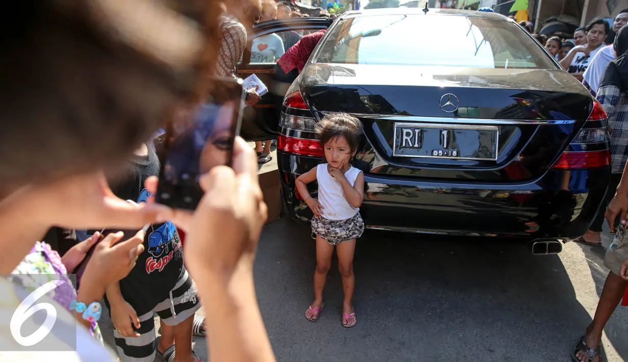 Seorang anak berpose di belakang mobil yang digunakan Presiden Joko Widodo dan Ibu Negara saat blusukan ke Kedoya dan Petamburan, Jakarta, Selasa (1/9/2015). (Liputan6.com/Faizal Fanani)