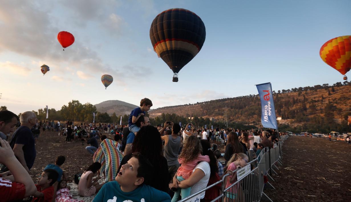 Sejumlah pengunjung menyaksikan Festival Balon Udara Gilboa di dekat Kibbutz Ein Harod, Lembah Jizreel, Israel (4/8). Festival balon udara ini menjadi tontonan menarik bagi warga sekitar dan wisatawan. (AFP Photo/Manahem Kahana)